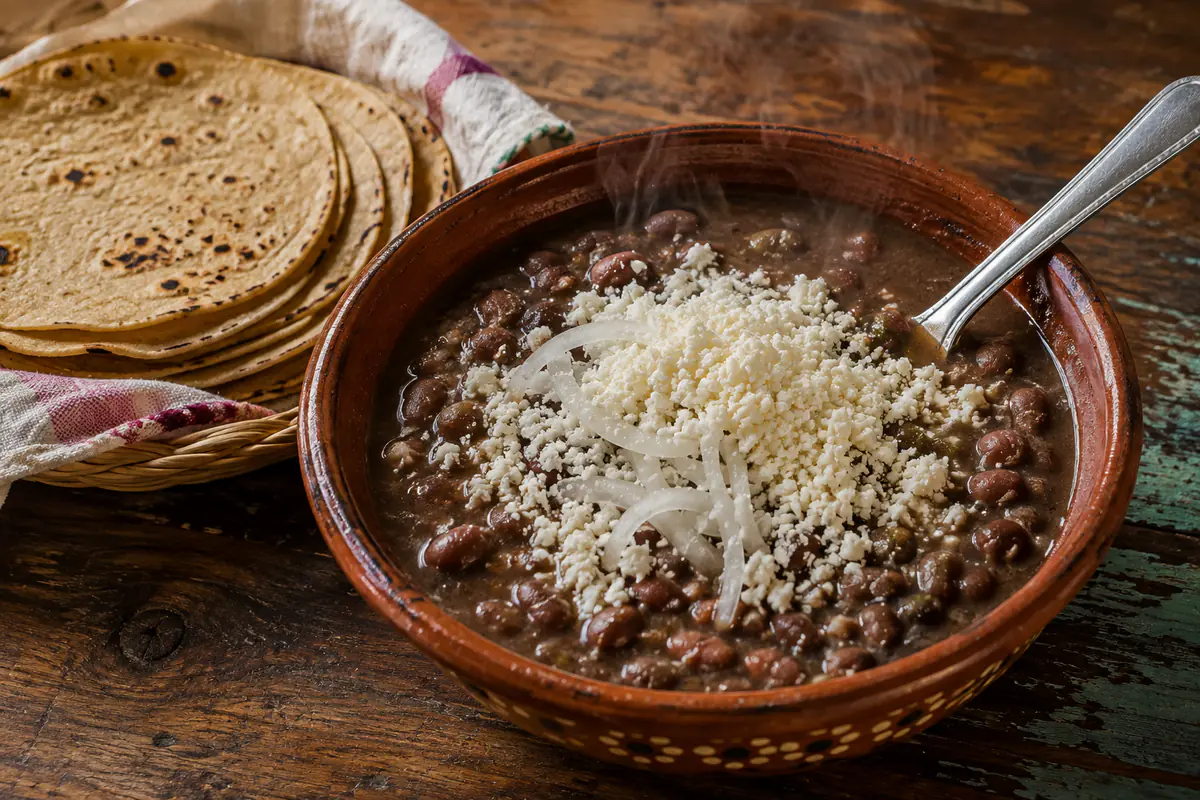 Cazuela de barro con frijoles de la olla, cebolla y queso cotija análogo desmoronado encima