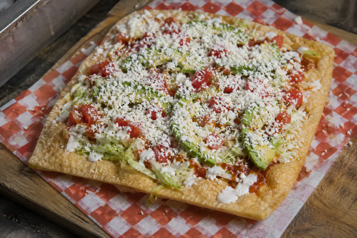 Chicharrón de harina preparado con crema, salsa, verdura y queso seco espolvoreado